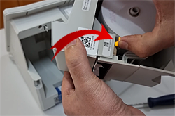 Imagem exibindo uma mão abrindo o módulo impressor e ajustando o papel da urna.